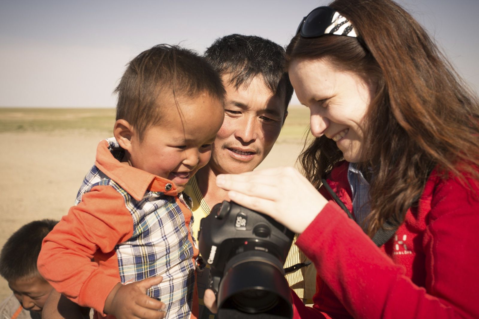 Fotoworkshop-Teilnehmerin zeigt mongolischem Papa und dessen Sohn, das von ihnen geschossenen Portrait.