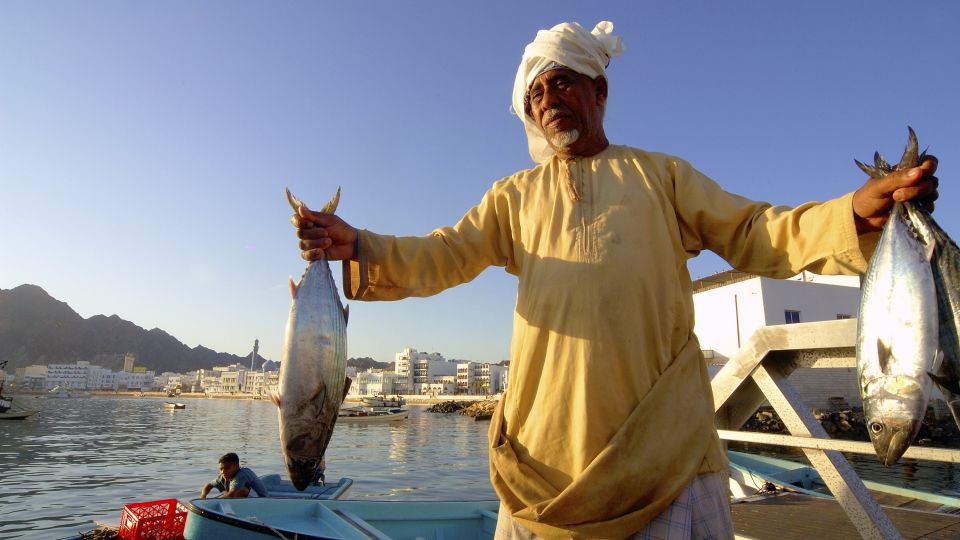 Omani mit Fisch auf dem Fischmarkt in Muttrah