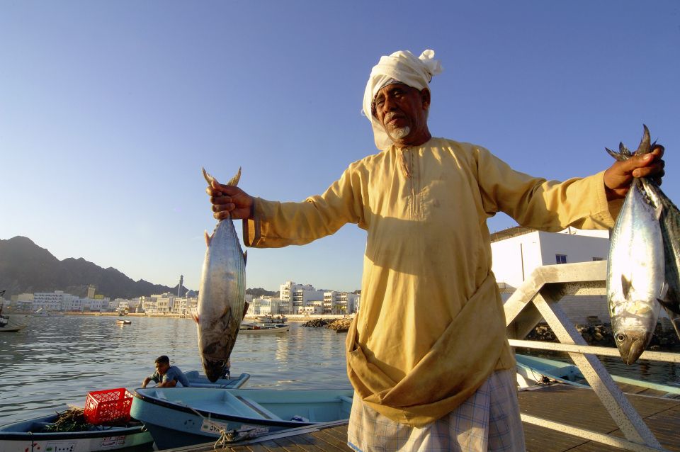 Omani mit Fisch auf dem Fischmarkt in Muttrah