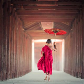 Junger Mönch mit rotem Schirm