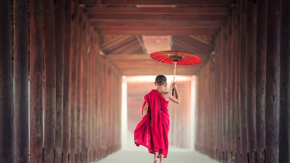 Junger Mönch mit rotem Schirm
