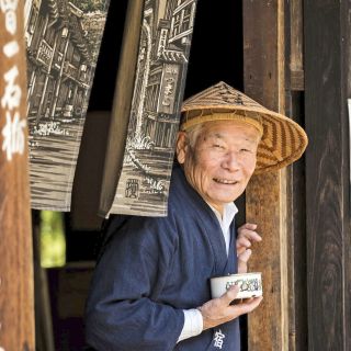 Ein freundlicher Japaner serviert in einem traditionellen Teehaus Tee für die vorbeikommenden Wanderer entlang des Nakasendo in Kiso.