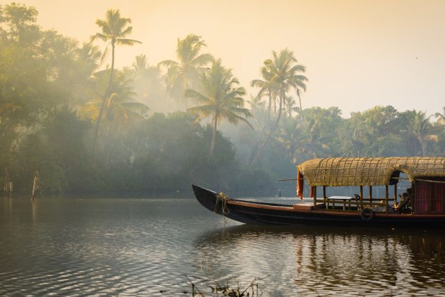 Ein traditionelles Hausboot am Ufer Flusses in Kerala