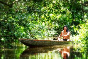 Indigener Ecuadorianer mit Einbaum im Regenwald