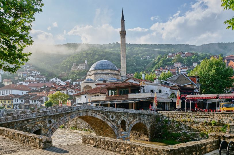 Die alte Steinbrücke überspannt die Bistrica. Im Hintergrund die Sinan-Pascha-Moschee und links auf dem Berg die Festung von Prizren.