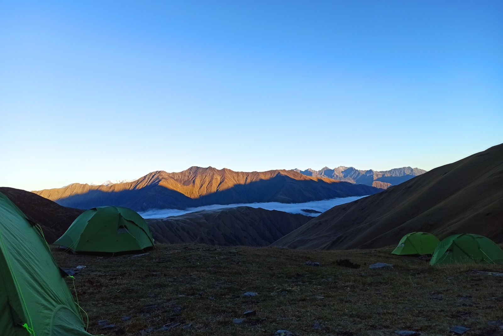 Hochgelegenes Zeltcamp mit Blick auf die von Sonnenstrahlen gekitzelten Bergspitzen, Georgien – Tuschetien