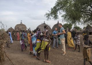 Reisende zu Besuch in einem Dorf im Südsudan