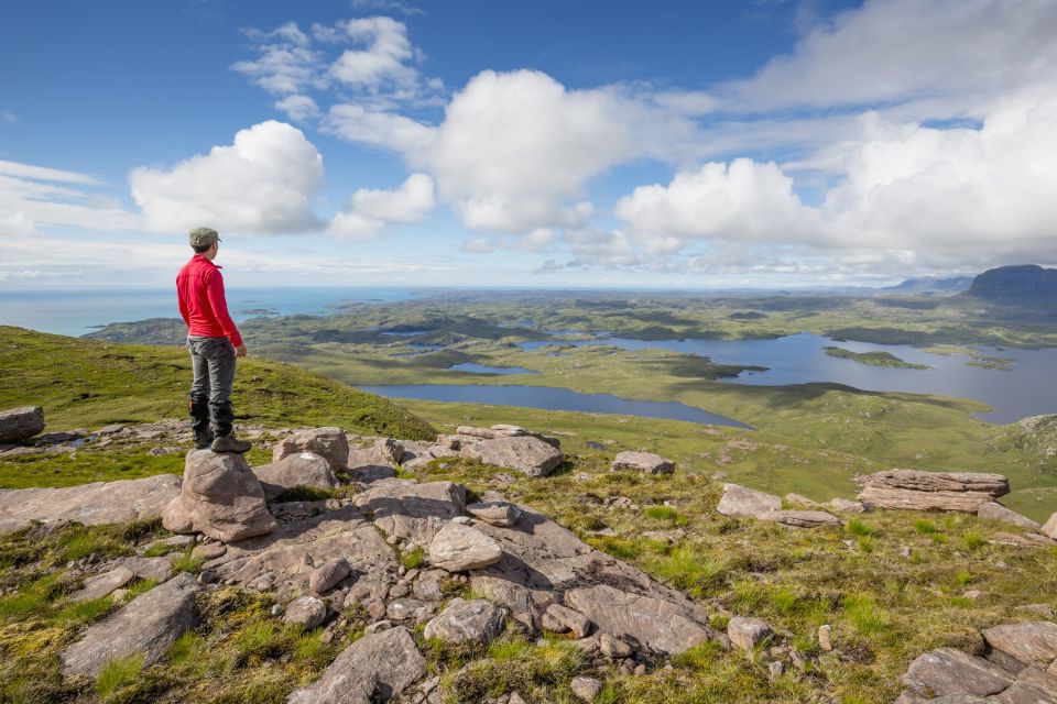 Wanderer genießt den Blick vom Stac Pollaidh über die Seenlandschaft, Wester Ross, nahe Ullapool