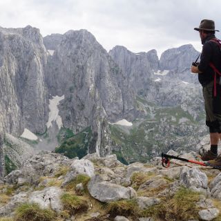 Wanderer vor ehrfurchtsgebietender Felswand im Prokletije-Nationalpark, Montenegro, oberhalb des Grbaja-Tals