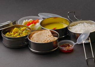 Typische Edelstahl-Lunchbox oder Tiffin mit Maharashtrian-Speisen Chapati oder Roti, Dal – ein Linsengericht, weißer Reis, Kartoffel-Sabji mit Salat und Gurke.