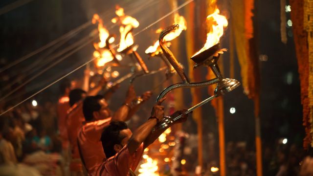 Hinduistische Priester schwenken große Kronleuchter zur Aarti-Zeremonie am Ganges in Varanasi.