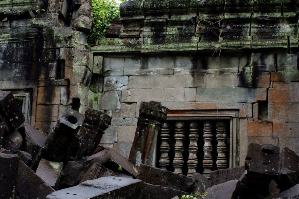 Die dicken Steinmauern der Tempelanlage werden von dichtem Dschungel und einem großen Teich umschlossen