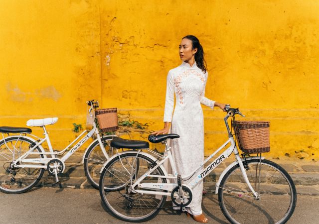 Junge Frau mit einem Fahrrad vor einer gelben Wand