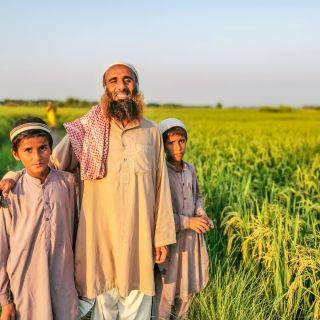 Asiatischer Landwirt mit seinen beiden Söhnen zwischen seinen Feldern