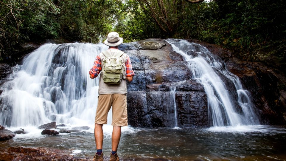 Wanderer steht vor einem Wasserfall im Dschungel, Sri Lanka